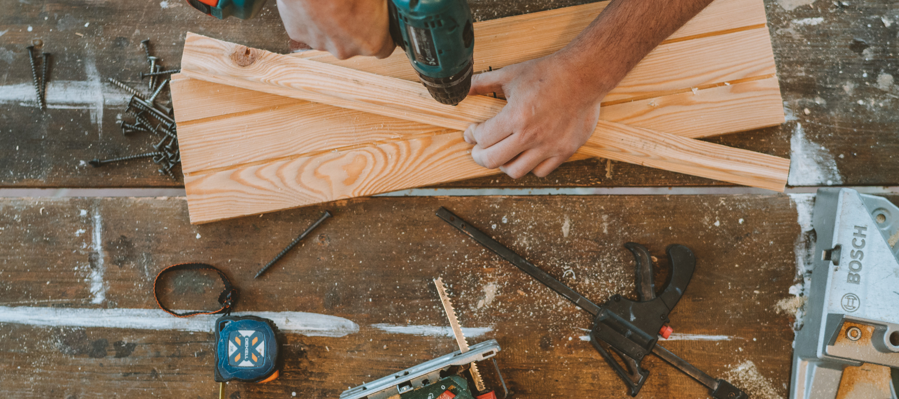 An arial view of a drill going into lumber surrounded by hand tools.