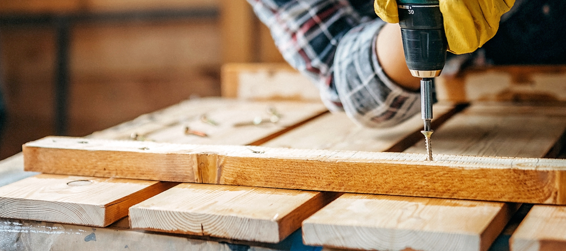 A power drill installing a wood screw into a lumber board.